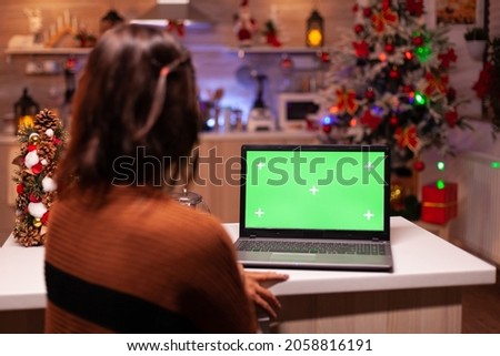 Young adult watching laptop device with green screen technology for mockup template app. Caucasian woman using notebook for digital chroma key isolated display on virtual gadget