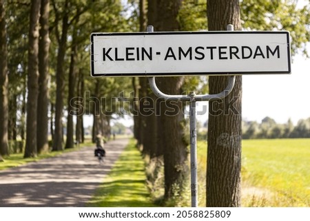 Bicycle rider out of focus passing by in lane with side of the road countryside municipality sign with name of the village 