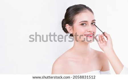 Makeup artist applies eye shadow. Professional Makeup artist works with brush on beautiful woman face in studio on white background, copy space. Make up in process.
