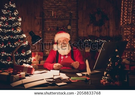 Photo of aged santa claus happy positive smile read letters wish workshop new year lights decor noel indoors
