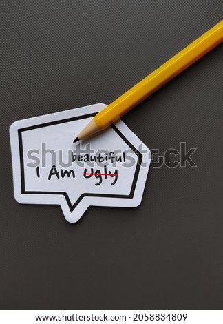 Note sticker , speech bubble with text written I AM UGLY changed to I AM BEAUTIFUL , concept of overcome negativity inner voice critics about self image which impact confidence, change to positive one