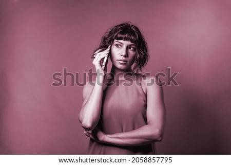 woman talking on her mobile phone – phone talk communication concept -  young people calling cell telephone -  young people talking on the smartphone – studio shot on violet background 