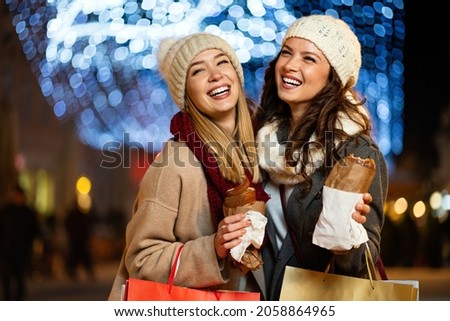 Portrait of happy women enjoying christmas fair and shopping together outdoors.