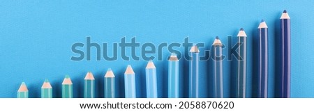 Pencils of different shades lie on blue background