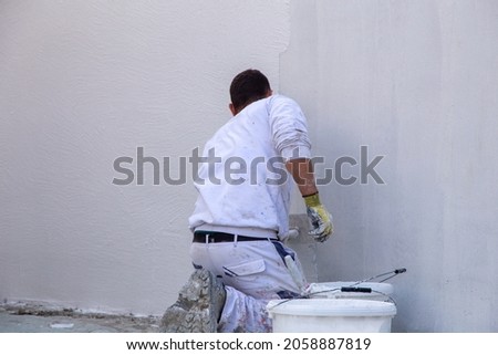 Plasterers plaster the facade of a new building
