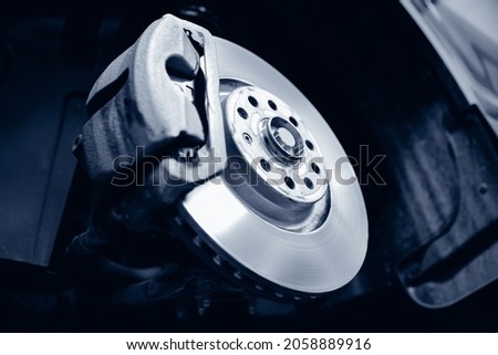 Closeup of steel brake disc in car service. Concept for replacing wheel pads in garage. Royalty-Free Stock Photo #2058889916
