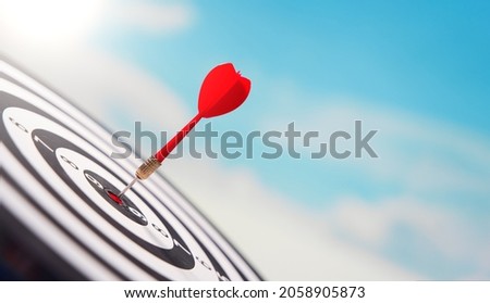 Red dart in center of target over sky Royalty-Free Stock Photo #2058905873