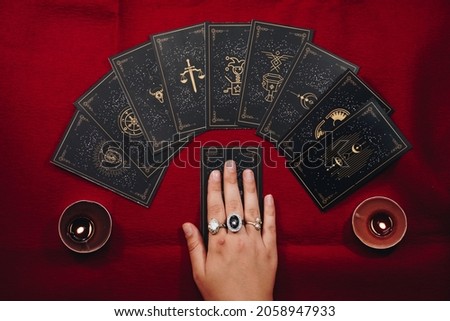 Fortune teller female hands and tarot cards on a red table. Divination concept.  Royalty-Free Stock Photo #2058947933