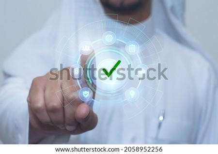 Saudi man indicates with his finger. E services touch screen with correct choice Royalty-Free Stock Photo #2058952256
