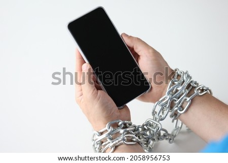 Hands wrapped in chain hold black smartphone closeup