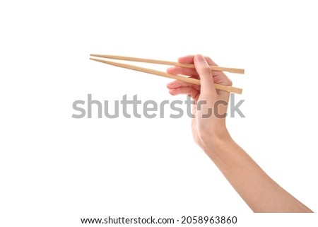 female hand holds Wooden chopsticks isolated on white background. Royalty-Free Stock Photo #2058963860