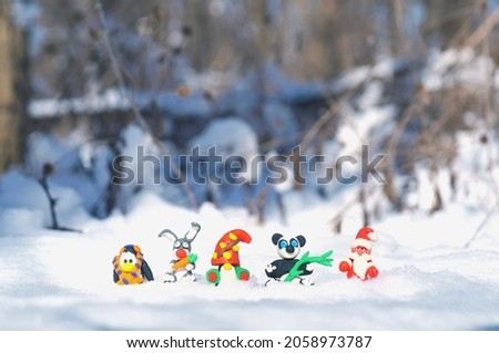 Figurines of fairy-tale characters in the winter forest. Santa Claus, a dwarf, a rabbit with a carrot, a panda, a penguin in a scarf.