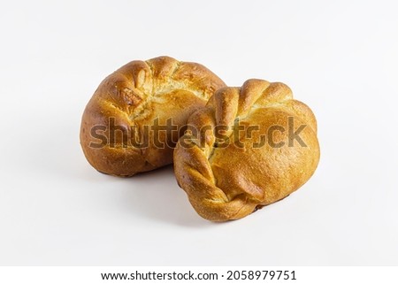 Dough pies with stuffing, with pinches in the form of a pigtail on a light background