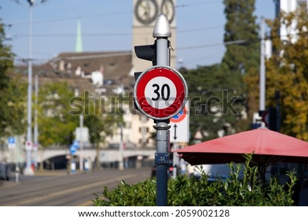 Speed limit sign 30 kilometers per hour at City of Zürich on a sunny autumn day with protestant church St. Peter in the background. Photo taken October 1st, 2021, Zurich, Switzerland.