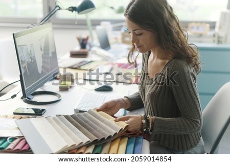 Professional decorator working in her studio, she is choosing fabric swatches for her project Royalty-Free Stock Photo #2059014854