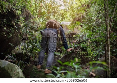 Asian man carrying a backpack hiking in the rainy season