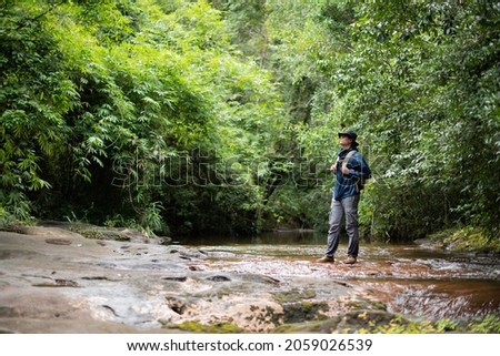 Asian man carrying a backpack hiking in the rainy season