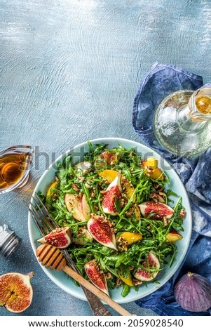 Autumn fig and arugula salad recipe. Whole vegan paleo fruit and vegetable fall salad idea. Homemade salad bowl with figs, arugula, peach and apple slices, nuts and honey Royalty-Free Stock Photo #2059028540
