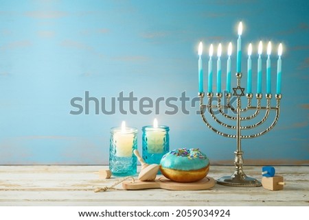 Jewish holiday Hanukkah concept with menorah, candles and traditional donuts on wooden table. Background for greeting card or banner