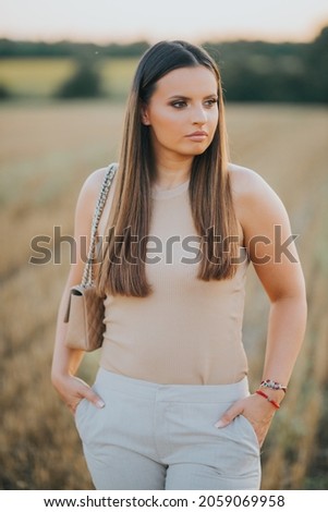 A vertical shot of a young Caucasian female model posing in a wheat field