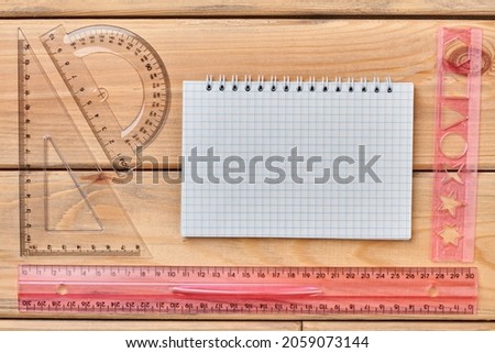 Desk with open notebook and plastic rulers.