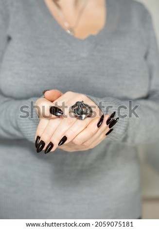 Woman's hands with long nails and black manicure with bottles of nail polish