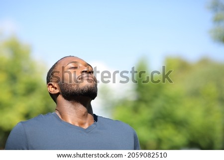 Man with black skin breathing fresh air in nature a sunny day Royalty-Free Stock Photo #2059082510