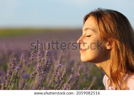 Side view portrait of a woman smelling flowers in a lavender field at sunset Royalty-Free Stock Photo #2059082516