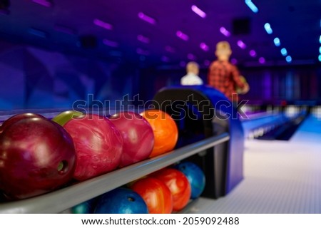 Bowling balls, two boys at the lane on background