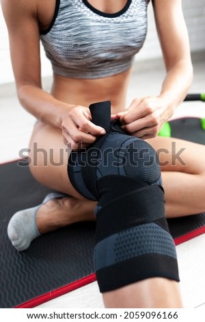 a sporty woman in a fixing knee pad for sports trains at home restores the knee