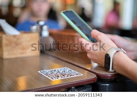 Closeup of guest hand ordering meal in restaurant while scanning qr code with mobile phone for online menu. Royalty-Free Stock Photo #2059111343