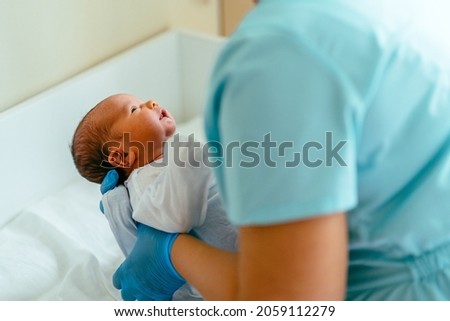 Doctor pediatrician examining new born baby boy in clinic. Nurse dressing infant baby boy. Medical checkup. Health care concept.