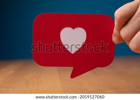 A hand showing a red speech bubble with heart - Valentine concept