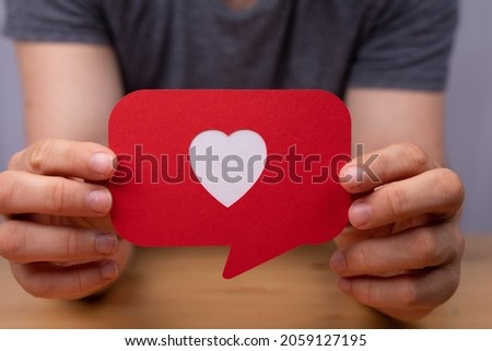 A hand holding a red speech bubble with heart - Valentine concept