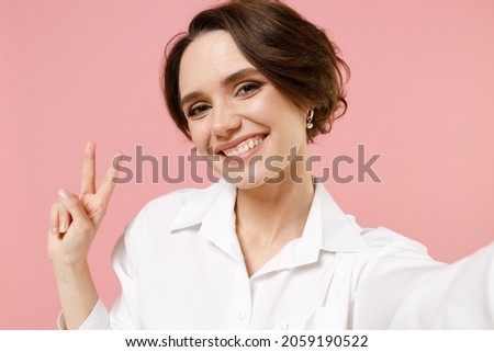 Close up smiling happy young employee business woman corporate lawyer in classic formal white shirt work in office doing selfie shot on mobile phone isolated on pastel pink background studio portrait