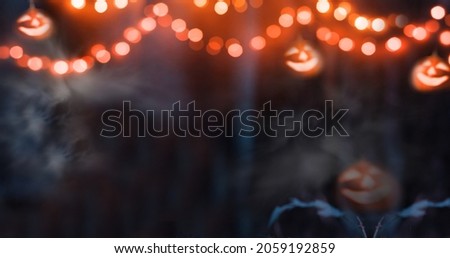 A magical background for Halloween with garlands with orange bokeh lights and glowing pumpkins. Mystical night forest in all saints day. Celebration concept with jack o lanterns. Copy space for text