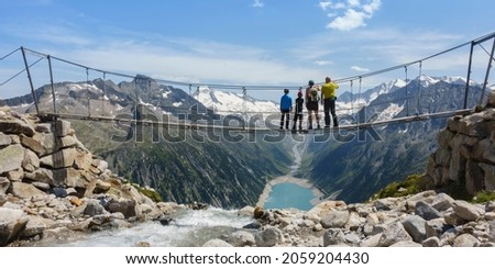 Panoramic picture of a family on a hike on the suspension bridge in the Zillertal with a view of the Schlegeis reservoir