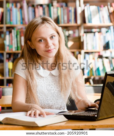 happy female student with laptop in library