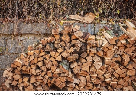 A pile of firewood stacked against the wall. Chopped wooden logs neatly stacked.