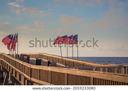 A landscape image of American flags waving in the wind on the Deerfield Beach Florida public pier