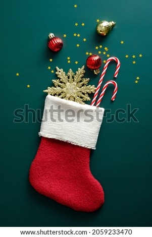 Christmas sock with gifts on dark green background. Flat lay, top view, overhead.