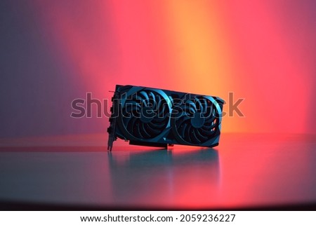 Black graphics card with two fans, on a wooden table, with red and blue lighting. Royalty-Free Stock Photo #2059236227