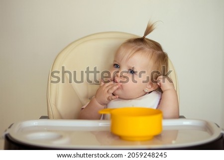 happy baby sitting at the table in the kitchen and eating with an appetite Royalty-Free Stock Photo #2059248245