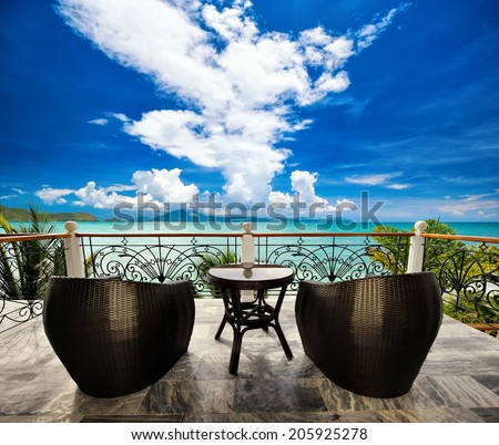 Terrace lounge with rattan armchairs and seaview in a luxury resort . Summer holiday concept Royalty-Free Stock Photo #205925278
