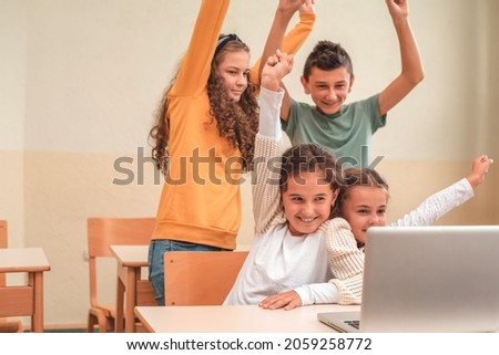 Happy group of school kids learning on laptop and smiling during the online class. Young students using a laptop. Selective focus