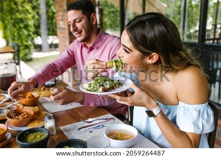 young latin woman eating mexican tacos on a restaurant terrace in Mexico Latin America, feeling happy on a summer day Royalty-Free Stock Photo #2059264487