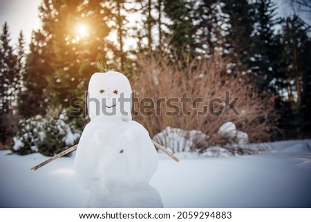 Snowman in sunny winter forest against the trees and white snow. New Year, Christmas active games outdoor.