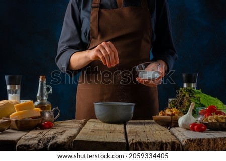 The chef is making a mustard sauce for a Caesar salad. Classic recipe. Lots of ingredients. Wooden texture. Step by step recipe, cookbook, cooking blog. Close-up. Color picture.