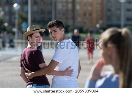 Gay angry teenager couple looking back to surprised woman. Homophobia in adolescence concept. Royalty-Free Stock Photo #2059339004