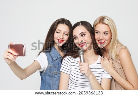 young women with a microphone singing and take picture with smartphone
